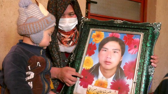 یو دوه کلن هلک د سلواغې په ۱۰مه په هرات ښار کې د خپل پلار عکس ته ګوري. پلار یې د ۱۴۰۱ د وري په میاشت کې د داعش په یوه برید کې ووژل شوی شو. [عمران/سلام ټایمز]