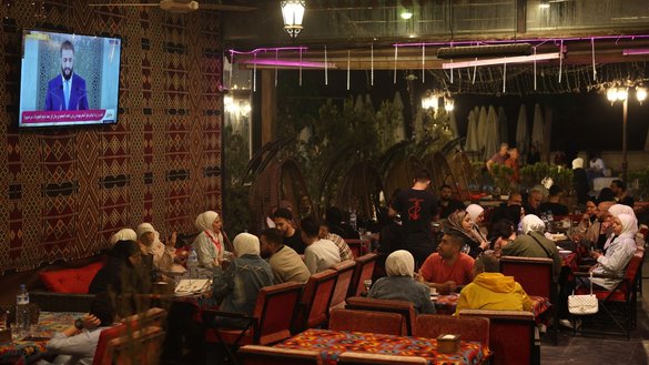 سوریه یان د غوایي په ۲۴مه، یوه ورځ وروسته له هغه چې د متحده ایالاتو ولسمشر ډونالډ ټرمپ اعلان وکړ چې هغه پر سوریه بندیزونه لیرې کوي، د حلب ښار په یوه رسټورانټ کې د سوریې د موقت مشر احمد الشرع تلویزیوني وینا ګوري. [عمر حاج کدور/ای اېف پي]
