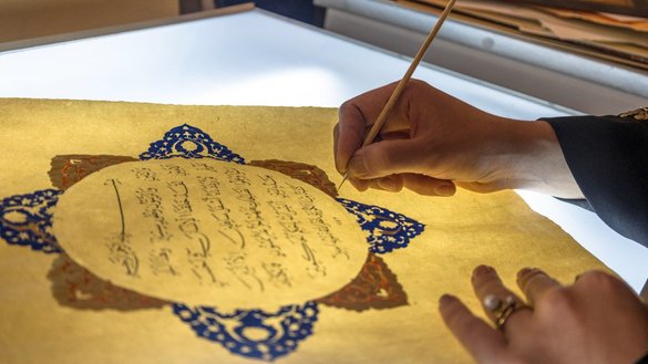یک هنرمند بتاریخ ۲۰ حمل در یک ورکشاپ صنایع دستی در هرات، افغانستان، روی صفحه‌ء از قران کریم روشنی می اندازد. [مصطفی نوری/تصاویر خاورمیانه از طریق خبرگزاری فرانسه]