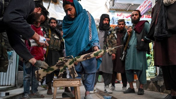 A man paints a rifle with a camouflage pattern in Kabul on November 21, 2021. [Hector Retamal / AFP]