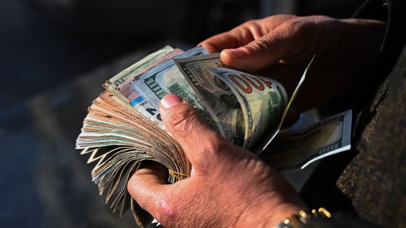یک صراف افغان در بازار تبادلهٔ اسعار کابل، بتاریخ 26 جنوری 2025، بانک نوتهای دالر امریکایی را می‌ شمارد. [وکیل کوهسار / AFP]